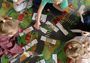 Dzieci w małych zespołach układają pocięte obrazki z dinozaurami.