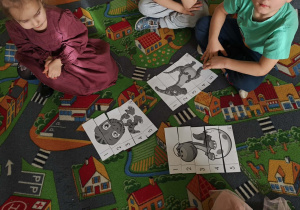 Dzieci w małych zespołach układają pocięte obrazki z dinozaurami.