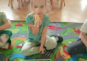 Dziewczynka pokazuje szkielet dinozaura.