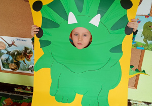 Dziecko pozuje do zdjęcia w ramce dinozaura.