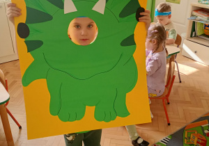 Dziecko pozuje do zdjęcia w ramce dinozaura.