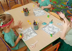 Dzieci wycinają i dopasowują odpowiednie części do obrazków z dinozaurami.