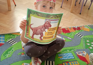 Dziecko pozuje do zdjęcia z pamiątkowym dyplomem.