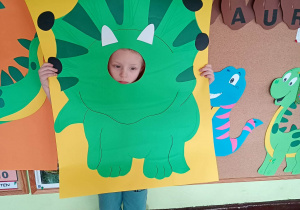 Dziecko pozuje do zdjęcia w ramce dinozaura.