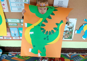 Dziecko pozuje do zdjęcia w ramce dinozaura.