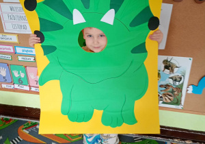 Dziecko pozuje do zdjęcia w ramce dinozaura.