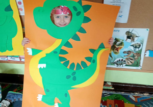 Dziecko pozuje do zdjęcia w ramce dinozaura.