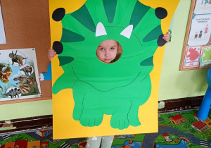 Dziecko pozuje do zdjęcia w ramce dinozaura.