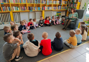 Dzieci słuchają opowieści pani bibliotekarki o wiośnie.