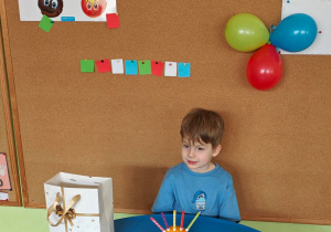 Chłopiec siedzi przy urodzinowym stoliku.