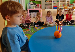 Chłopiec zastanawia sie nad urodzinowym życzeniem, zanim zdmuchnie świeczki.