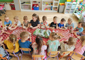 Dzieci siedzą przy stoliu i oczekują na dalsze instrukcje.