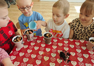 Dzieci podlewają zasadzoną cebulkę.