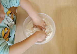 Dziecko poszukuje ukrytych przedmiotów w pojemniku z solą.