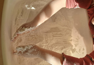 Dziecko poszukuje ukrytych przedmiotów w pojemniku z mąką.