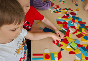 Dzieci układają figury geometryczne w dowolny sposób, tworząc z nich ciekawe obrazki.