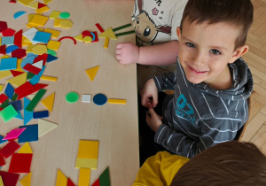 Dzieci układają figury geometryczne w dowolny sposób, tworząc z nich ciekawe obrazki.