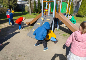Dzieci szukją w przedszkolnym ogrodzie ukrytych przez zajączka czekoladowych jajaeczek.