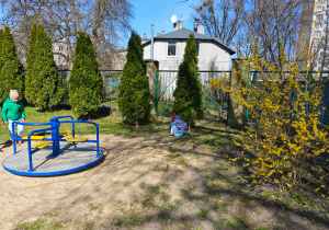 Dzieci szukją w przedszkolnym ogrodzie ukrytych przez zajączka czekoladowych jajaeczek.