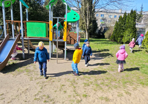 Dzieci szukją w przedszkolnym ogrodzie ukrytych przez zajączka czekoladowych jajaeczek.