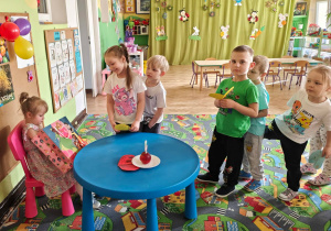 Dzieci wręczają Adzie laurki i składają życzenia.