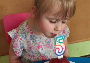 Dziewczynka sprawdza zapach urodzinowej świeczki.