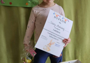 Dziewczynka prezentuje dyplom i nagrodę za 1 miejsce w przeglądzie ogólnopolskim.