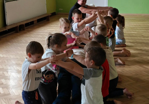 Dorośli przedostają się pod mostem stworzonym przez dzieci.