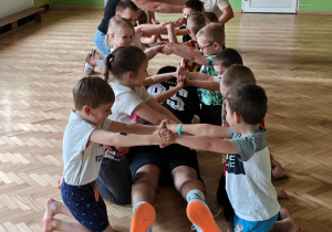 Dorośli przedostają się pod mostem stworzonym przez dzieci.