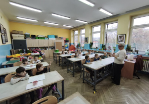 Dzieci siedzą w ławkach szkolnych