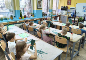 Dzieci siedzą w ławkach szkolnych