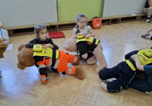 Dzieci ćwiczą na misiach sposób zachowania przy zadławieniu.