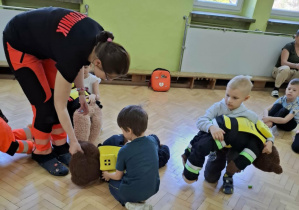 Dzieci ćwiczą na misiach sposób zachowania przy zadławieniu.