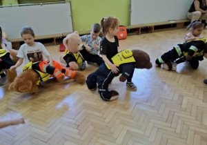 Dzieci ćwiczą na misiach sposób zachowania przy zadławieniu.