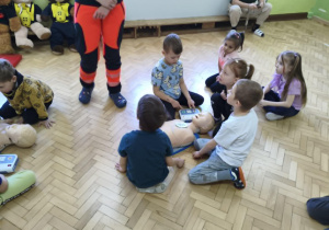 Dzieci ćwiczą obsługę urządzenia AED.