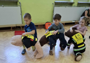 Dzieci ćwiczą na misiach sposób zachowania przy zadławieniu.