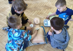 Dzieci ćwiczą obsługę urządzenia AED.