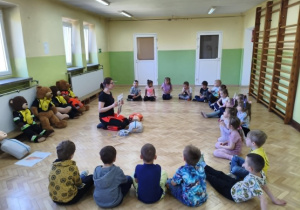 Ratownik prezentuje dzieciom sposób obsługi urządzenia AED.