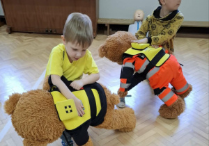 Dzieci ćwiczą na misiach sposób zachowania przy zadławieniu.