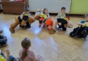 Dzieci ćwiczą na misiach sposób zachowania przy zadławieniu.