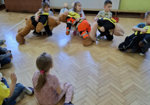 Dzieci ćwiczą na misiach sposób zachowania przy zadławieniu.