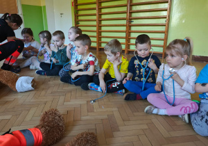 Dzieci przy użyciu stetoskopów słuchają bicia swojego serduszka.