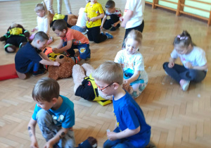 Dzieci udzielają misiom pierwszej pomocy i naklejają im plasterki.