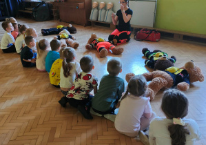 Ratownik prezentuje dzieciom, sposób postępowania w przypadku małego skaleczenia.