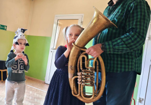 Dziewczynka próbuje zagrać na tubie.
