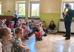 Dzieci słuchają malodii wygrywanej na tubie.