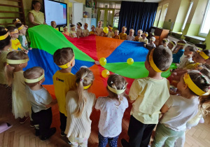 Dzieci bawią się z wykorzystaniem chusty animacyjnej i żółtych balonów.