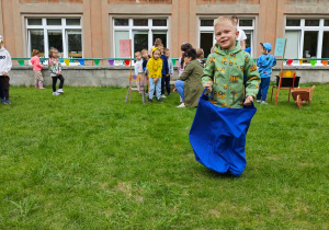 Dziecko pokonuje tor przeszkód, skacząc w worku.