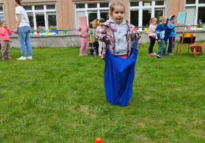Dziecko pokonuje tor przeszkód, skacząc w worku.