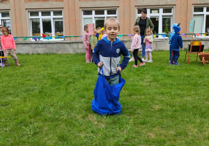 Dziecko pokonuje tor przeszkód, skacząc w worku.